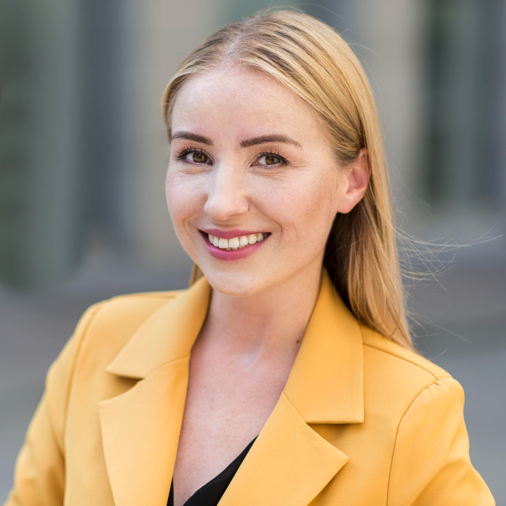 Person wearing a yellow blazer and smiling.