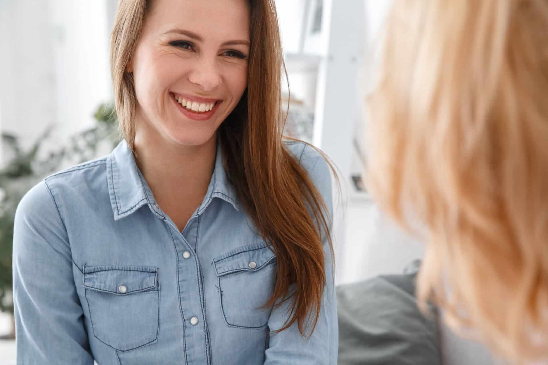 Person wearing a denim shirt and smiling.