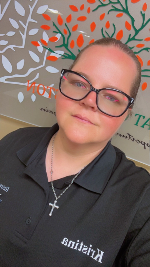 Person wearing black polo shirt with glasses and cross necklace.
