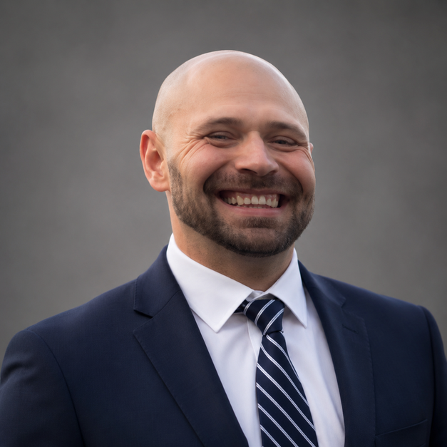 Person wearing a suit and tie, smiling.