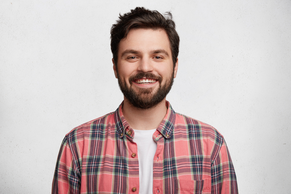 Person wearing a red checkered shirt and smiling.