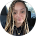 Person with braided hair wearing a black hoodie and a necklace.