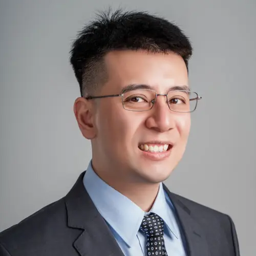Person wearing a suit and glasses smiling.